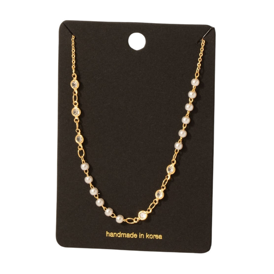 The CZ and Pearl Station Necklace by FASHION GO features a gold chain adorned with pearl stations and clear cubic zirconia gems, elegantly presented on a black card labeled "handmade in Korea.