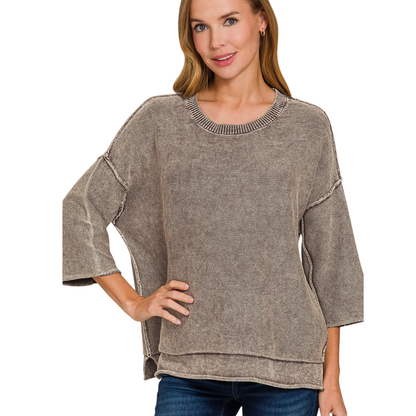 A woman models the Zenana Washed 3/4 Sleeve Boxy Cotton Sweater in beige, featuring a loose fit and layered hem, paired with blue jeans for a relaxed, oversized style.