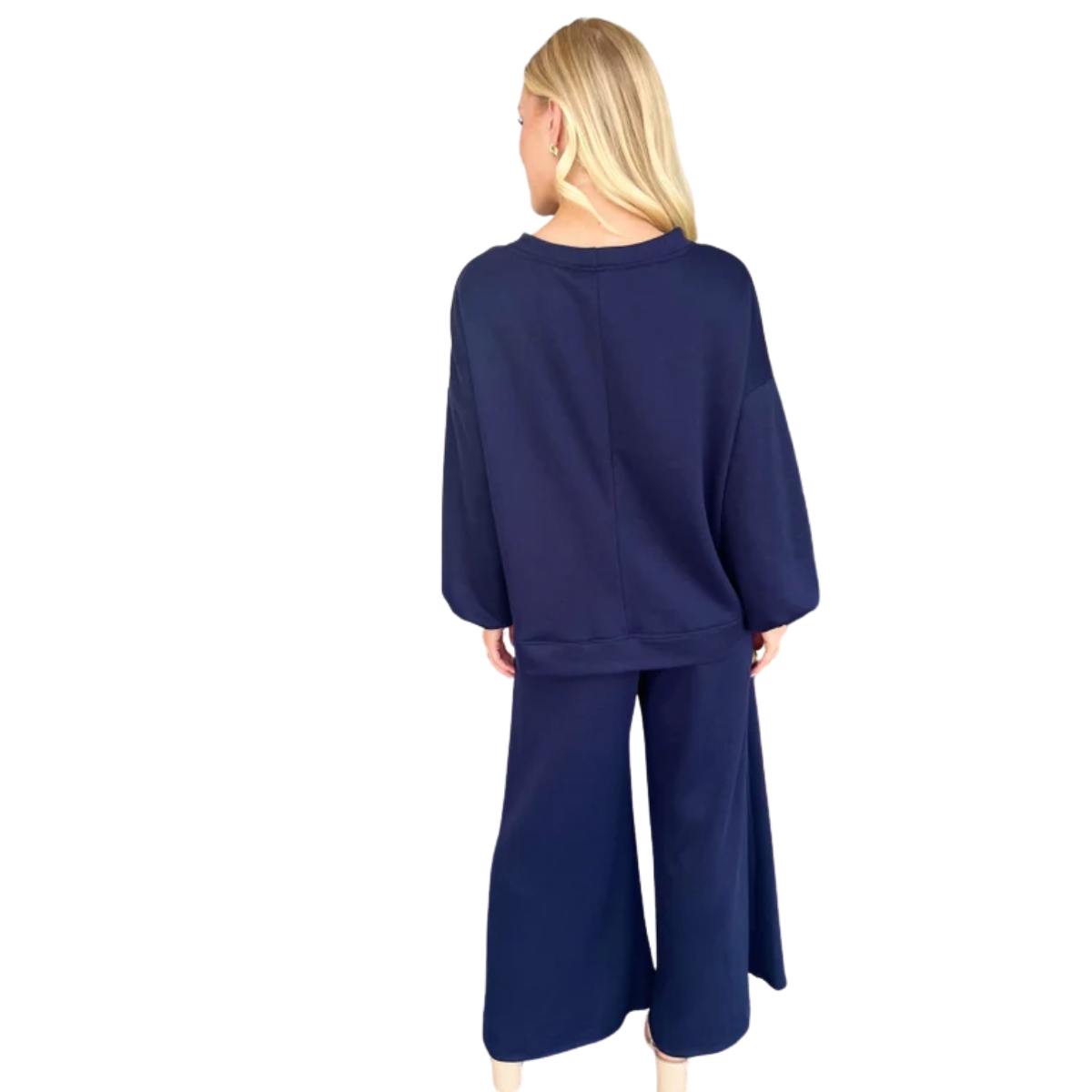 A woman stands facing away, wearing the Carole Christian Terry Wide Leg Set in Navy—a relaxed fit long-sleeve top and wide-leg pants—set against a white background.