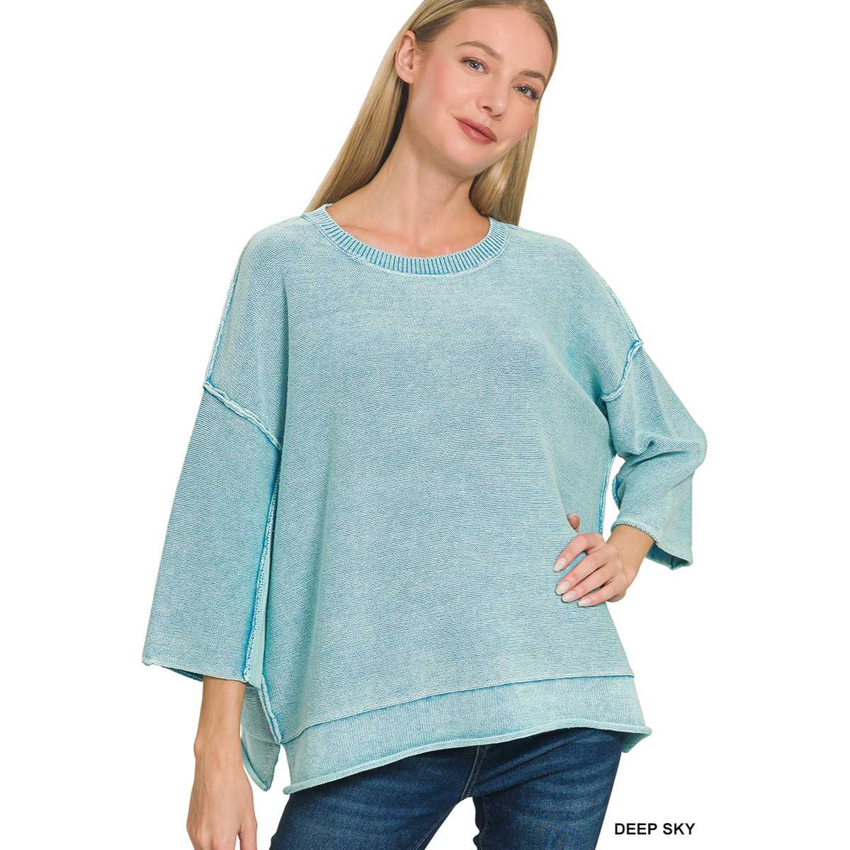 A woman models the Zenana Washed 3/4 Sleeve Boxy Cotton Sweater, featuring wide sleeves and a layered hem, paired with blue jeans for an easy oversized look against a white background.