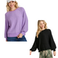Two women stand against a white background: one wears the Umgee Puff Sleeve Boat Neck Sweater in light purple with jeans and a cap, while the other pairs a black polyester-acrylic sweater with a floral skirt.