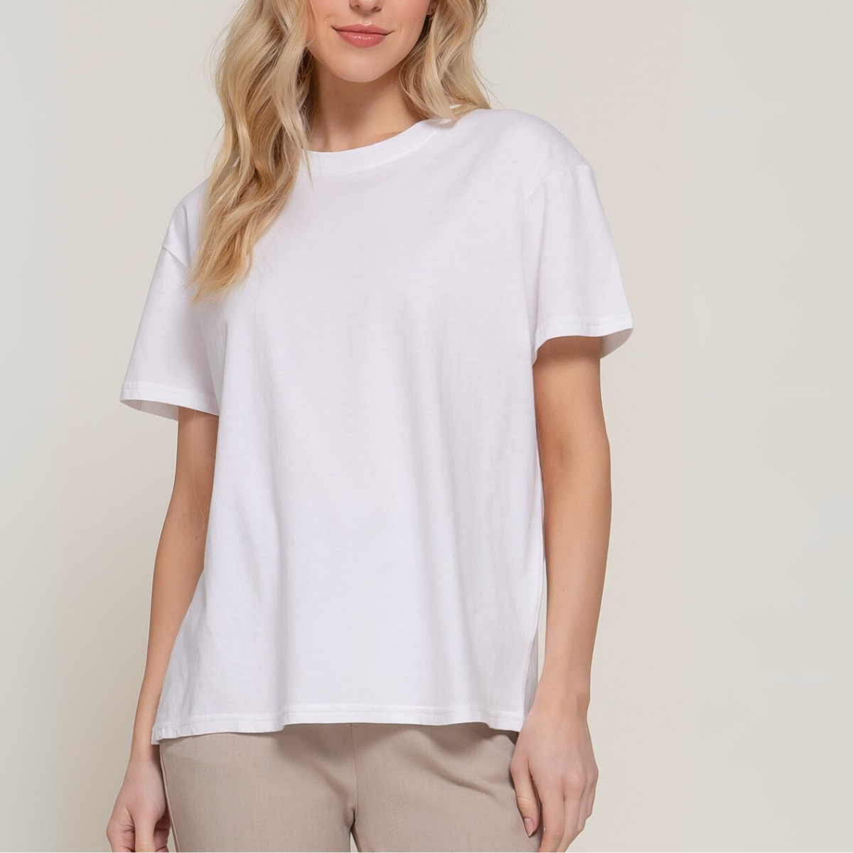 A woman wears the FASHION GO Short Sleeve Round Neck Tee in plain white cotton with beige pants, standing against a neutral background. Main image