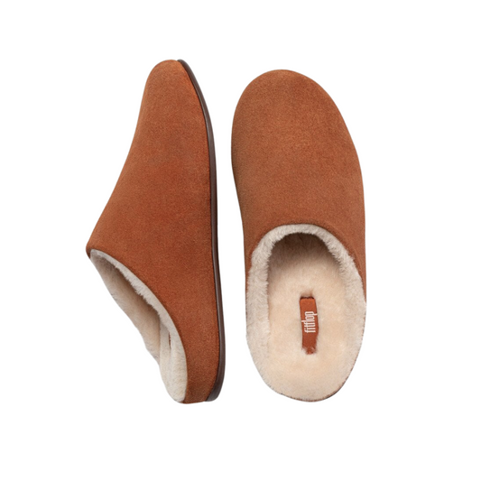 The Chrissie Shearling Slipper Clog in Tumbled Tan by FITFLOP USA LLC features cozy brown suede and cream shearling, shown from side and top views on a white background, offering signature FitFlop comfort for ultimate relaxation.