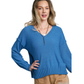 A woman wears the FASHION GO V-Neck Long Sleeve Sweater with Side Slits, featuring a textured, loose fit in blue with ribbed hem, paired with tan pants.