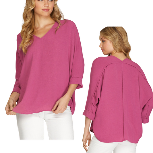 Two views of a woman wearing the She & Sky Drop Shoulder Air Flow Blouse in Soft Magenta, a loose-fitting, long-sleeve top with a V-neck, paired with white pants. The front view shows her looking forward, while the back view shows her looking to the side.