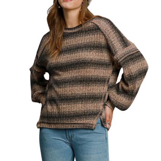 A person wearing a Striped Brushed Knit Long Sleeve Top by Umgee in latte colors and blue jeans stands with one hand in their pocket.