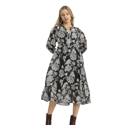 A woman in the Umgee Floral Print Boho Midi Dress, featuring long sleeves and a black-and-white pattern, pairs it with brown ankle boots against a white background.