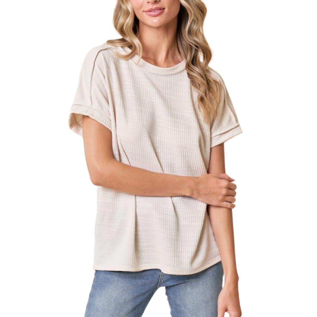 A woman wearing the Hanas Short Sleeve Top in Ivory by FASHION GO, made from a soft polyester blend, along with blue jeans, stands with one arm crossed over her waist.