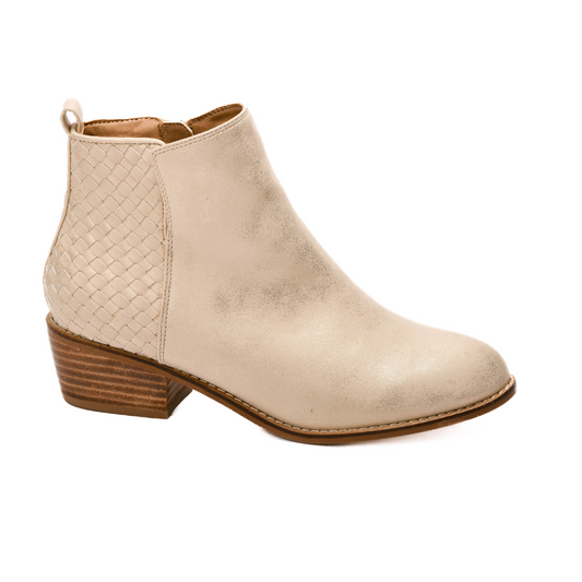 The Half and Half Ankle Bootie in Gold Metallic by Corky's from CORKY'S FOOTWEAR INC features a sleek gold ankle boot with a subtle woven design on the heel and a low wooden block heel, creating a fashion-forward look.