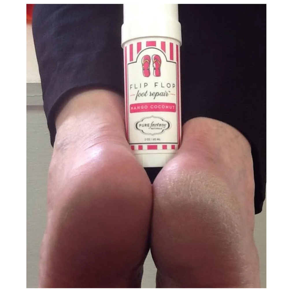 Close-up of two feet with a 1.75oz Flip Flop Essential Oils Foot Repair bottle in mango coconut scent by PUREfactory Naturals placed between the heels.