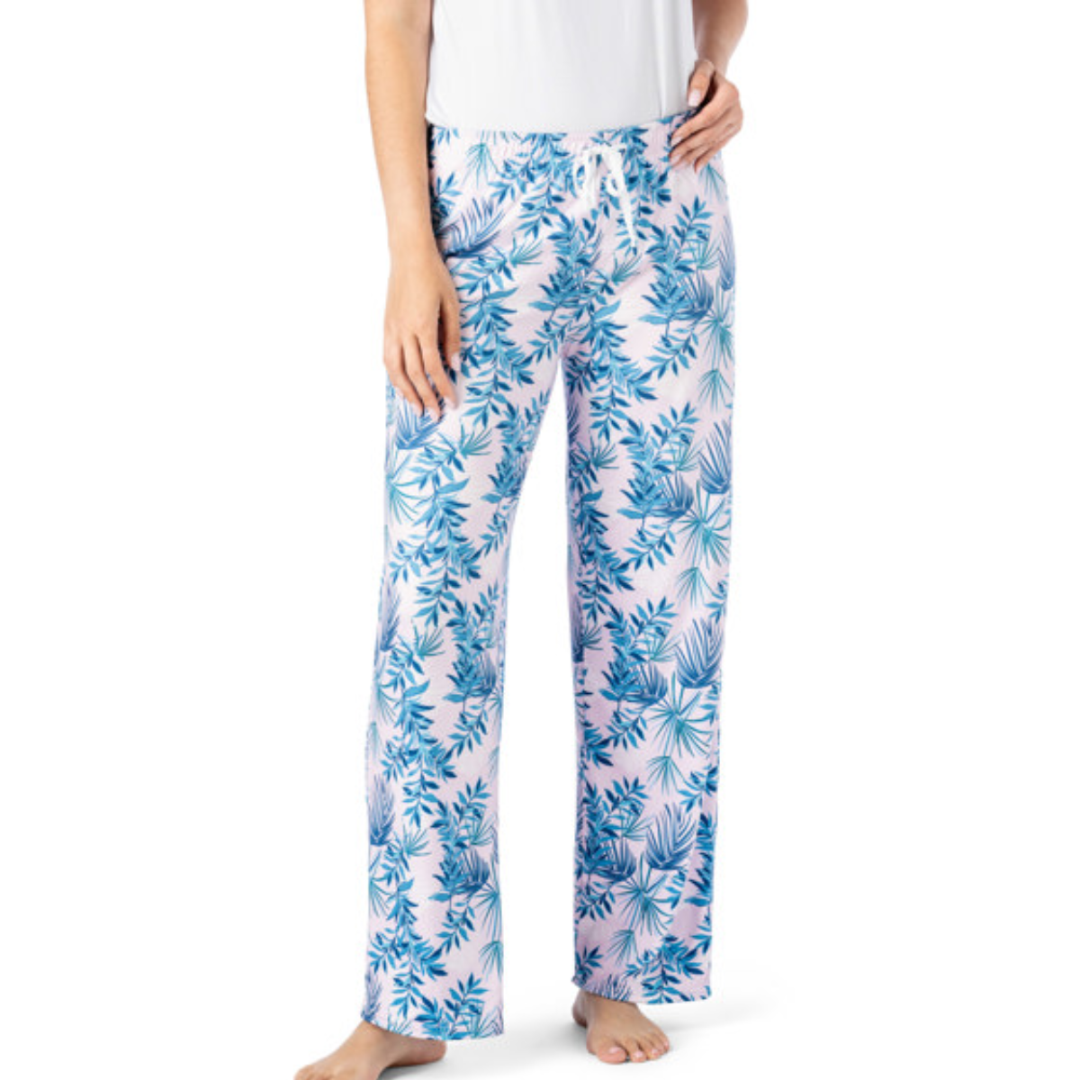 A person stands barefoot against a plain background, wearing Hello Mello Lounge Pants Spring Edition by DM MERCHANDISING INC, featuring ultra-soft blue leaf patterns. The relaxed fit of these pants adds effortless comfort to their calming presence, paired with a white top.