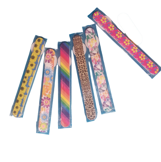 Six vibrant and patterned PATTERNED NAIL FILE EMORY BOARD files from GIFTCRAFT spread out, showcasing designs such as sunflowers, daisies, rainbow, leopard print, floral, and retro flowers. Each is housed in its own blue plastic sleeve.