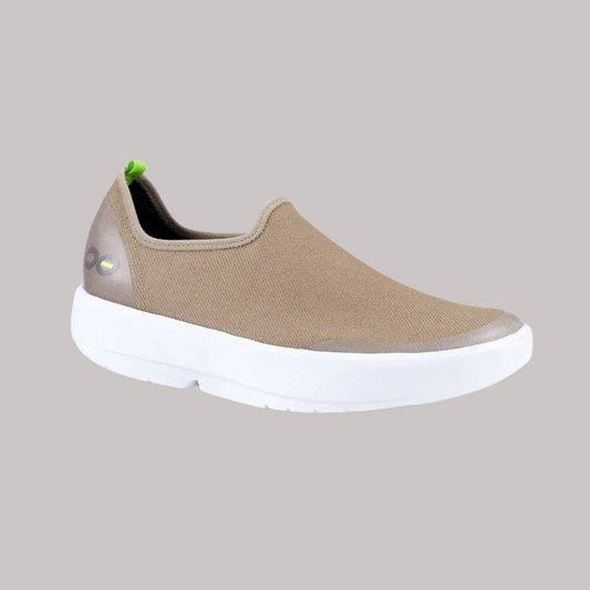 The OOFOS OOMG EASY LOW TAUPE from OOFOS LLC showcases a taupe slip-on design, complemented by a white sole and a subtle green tag on the heel, providing unparalleled comfort with its 4-way stretch feature.