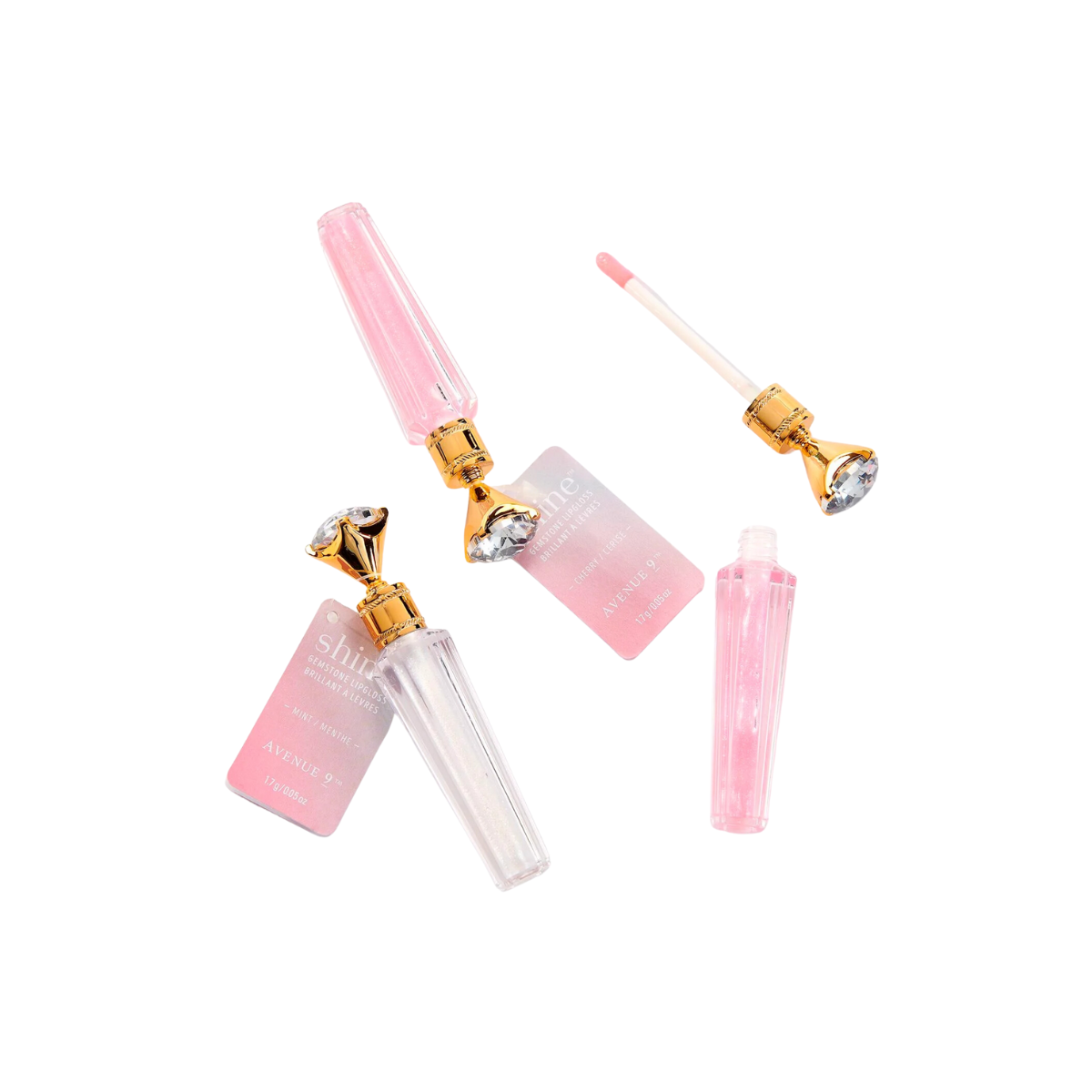 Two ornate Shine Gemstone Lip Gloss tubes by GIFTCRAFT, in pink and clear with luxurious gold caps, one open with the wand beside it, are displayed on a white background. These tubes promise shimmering glossy color for a touch of elegance.