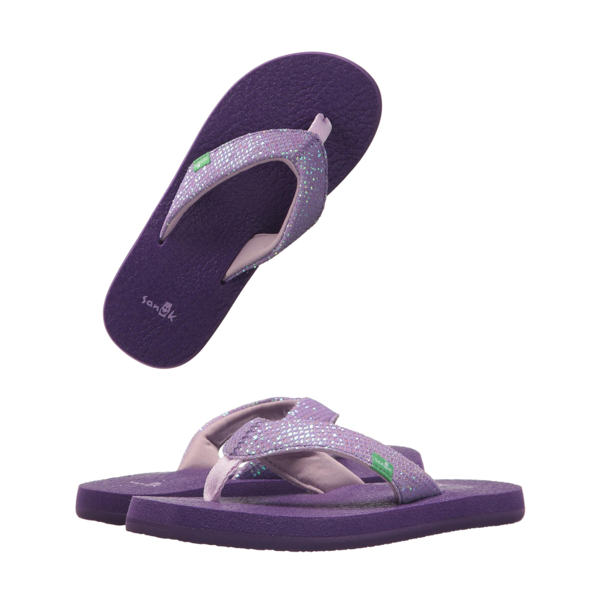 The SANUK YOGA GLITTER PURPLE flip-flops by Sanuk - Deckers are displayed, demonstrating the ultimate comfort of Yoga Mat Sandals. One pair stands upright while another tilts above, emphasizing their stylish design and glitter straps.