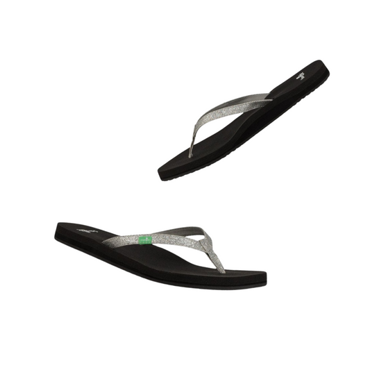 The Yoga Joy Flip Flops in Silver Sparkle by Sanuk, featuring a black base with silver straps, are displayed against a white background.