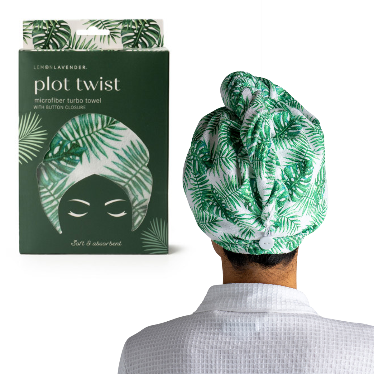 A person wearing the Plot Twist Turbo Towel by DM MERCHANDISING INC, featuring a green and white leaf pattern, enjoys hands-free drying with this microfiber hair towel. The matching towel packaging is displayed beside them.