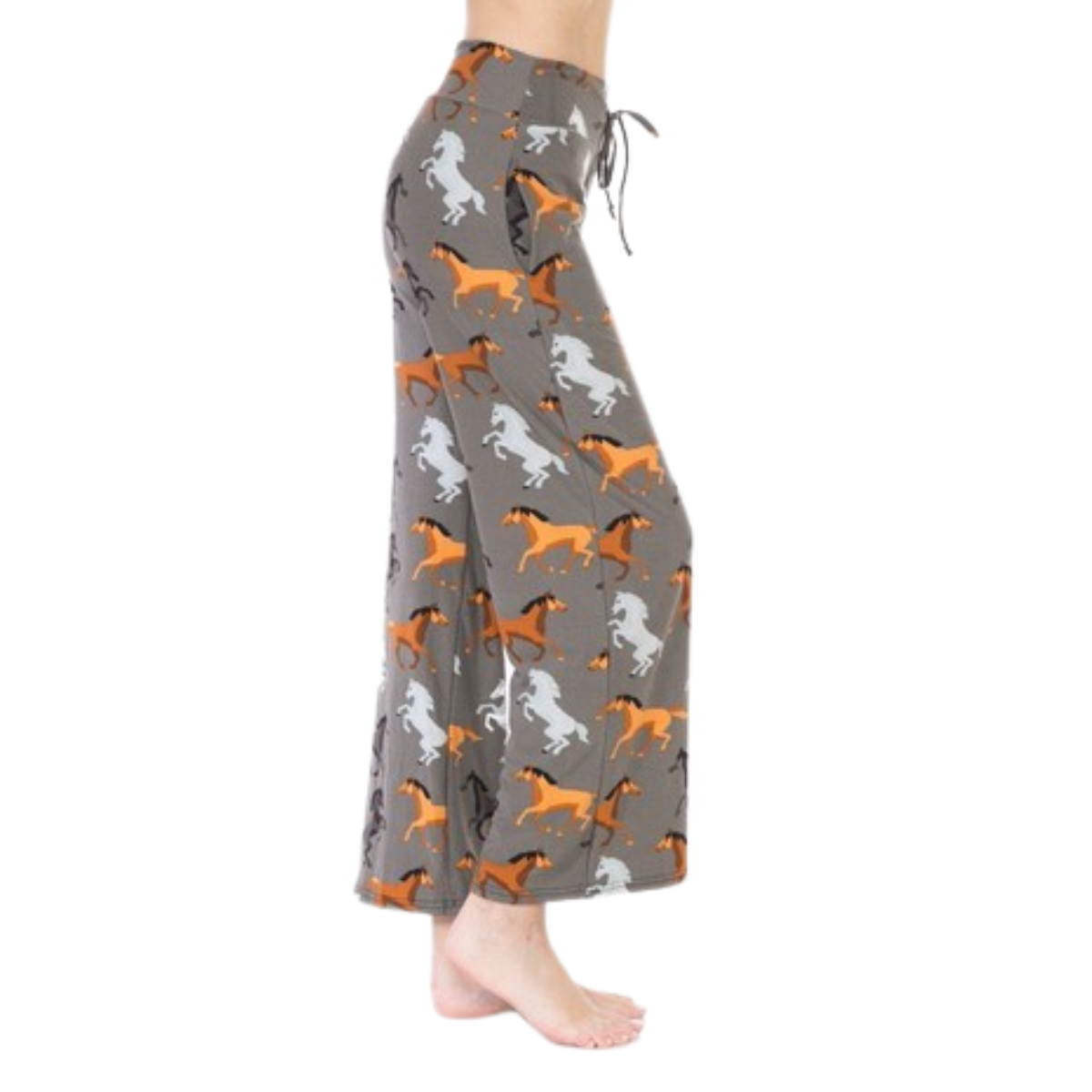 Person wearing FASHION GO Buttery Soft Pajama Pants with Drawstring, featuring a gray background and an orange and white horse print, standing barefoot.