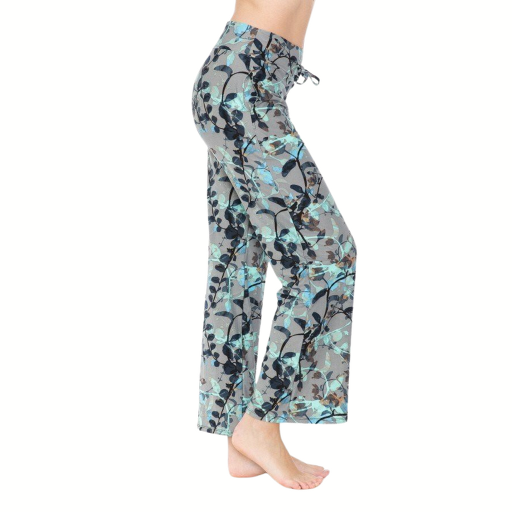 A person is shown from the side, barefoot on a white background, wearing FASHION GO Buttery Soft Pajama Pants with Drawstring featuring a loose fit and gray and blue floral pattern.