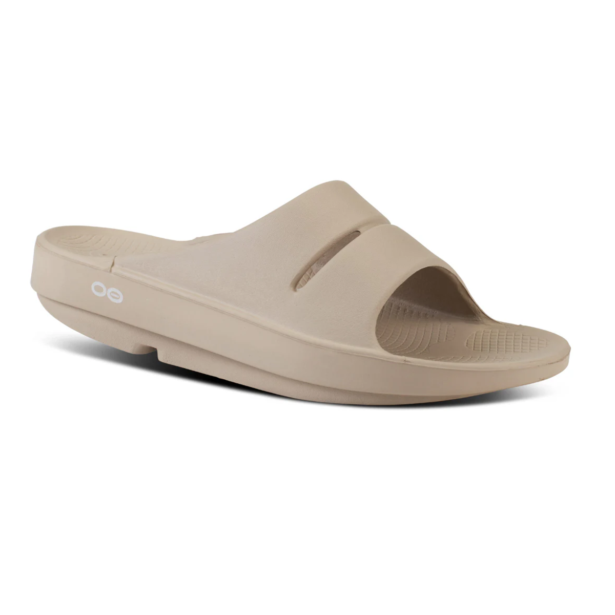 The Women's OOfos OOahh Slide Sandal - Nomad by OOFOS LLC is a beige sandal with a thick sole, patented footbed for impact absorption, two cutouts on the upper, and a textured footbed, shown in a side view.