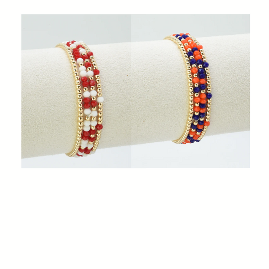 The FASHION GO Set of 4 Glass Bead and Gold Stretch Bracelets, featuring red, white, blue, and gold beads, is perfect gameday jewelry to add a festive touch to your look.
