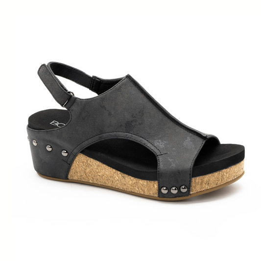 The Volta II in Black Metallic by CORKY'S FOOTWEAR INC showcases a cork wedge sole, side metal studs, and an adjustable slingback strap, shown on a white background.