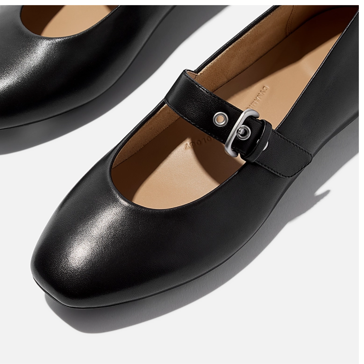 Close-up of the Delicato Leather Mary Janes in All Black by Fit Flops, featuring black nappa leather, a rounded toe, and adjustable buckle strap, displayed on a light background.