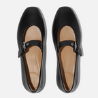 Delicato Leather Mary Janes in All Black by Fit Flops—a black nappa leather pair with square toes, single instep strap, and Dynamicush cushioning—shown from above on a white background.
