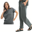 A woman models the Mono B Laguna Cowl Neck Wide Leg Pant Set—a matching dark gray lounge set with a cowl-neck short-sleeve top and wide leg drawstring pants, styled with black sandals against a white background.