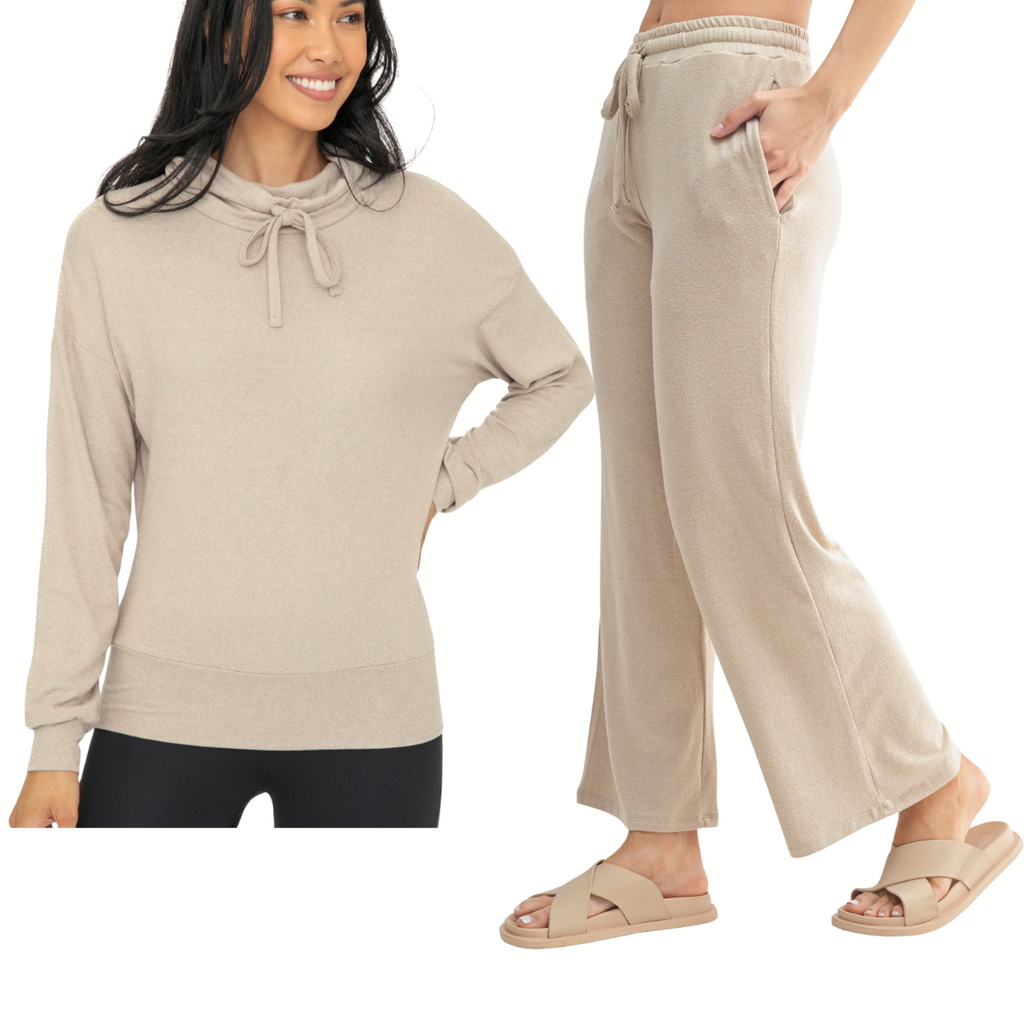 Two women model the Mono B Brushed Cowl Neck Lounge Pullover and Wide Leg Lounge Pant Set, crafted from soft Hacci fabric and shown in light beige with sandals against a white background.