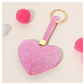 The Wona Trading Bling Heart Key Chain Bag Charm in assorted colors features rhinestones and a gold ring, shown with pink and white pom-poms—a stylish accessory to add sparkle to your bag or keys.
