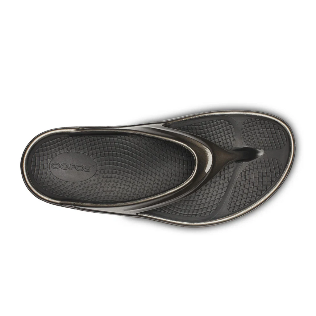 The OOFOS LLC OOmega OOlala in Titanium Mirror is a flip-flop sandal, shown from above on a white background, featuring a textured footbed, thong-style strap, and OOfoam™ technology for superior cushioning and arch support.