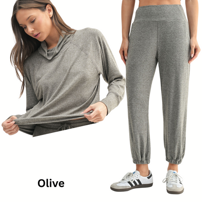 A woman wears the Mono B Brushed Hacci Cowl Neck Pullover and Jogger Set, featuring a cozy cowl neck top and elastic-cuff joggers in gray. "Olive" is displayed at the bottom left.
