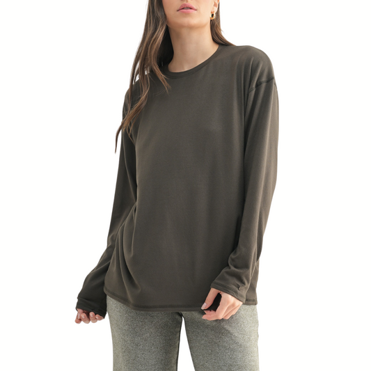 A person wears the monob Cozy Boyfriend Fit Hacci Long Sleeve Top in dark olive with light gray pants, standing against a white background.