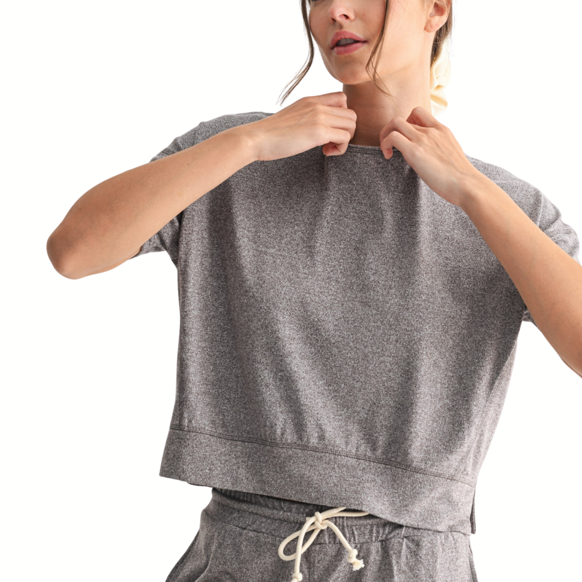 Person adjusting the collar of the FASHION GO Brushed Hacci Dolman Top in Espresso, a loose-fitting crewneck lounge top, paired with matching drawstring pants against a plain white background.