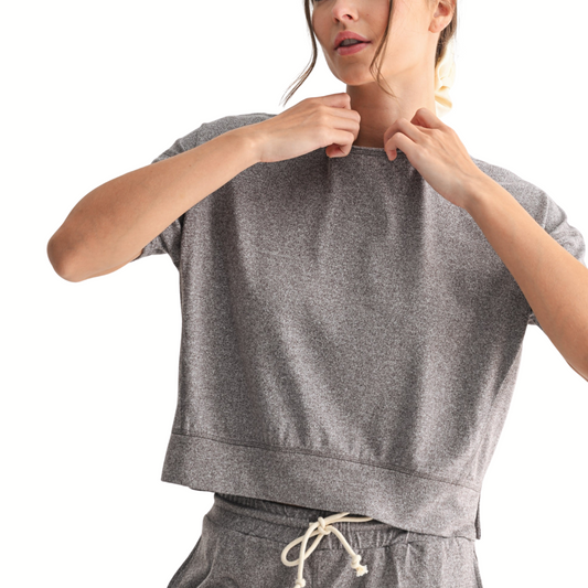 Person adjusting the collar of the FASHION GO Brushed Hacci Dolman Top in Espresso, a loose-fitting crewneck lounge top, paired with matching drawstring pants against a plain white background.