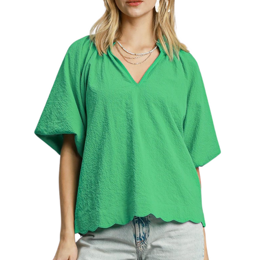 A woman wears the Umgee Bubbled Sleeved Seersucker Top in Green—featuring bubble sleeves and a scalloped hem—paired with light denim jeans and layered necklaces.