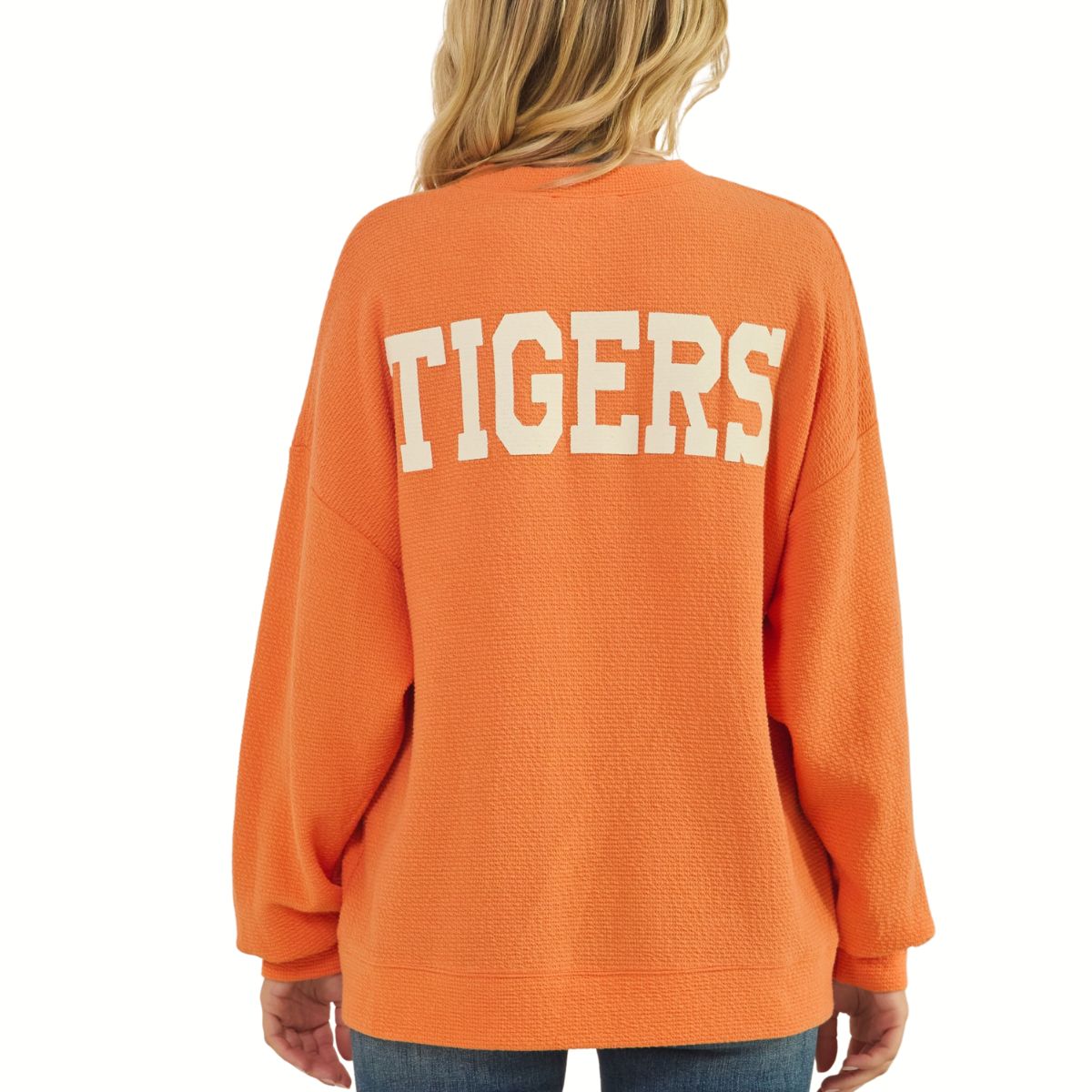 A football fan is seen from behind wearing the Tres Bien Paw Print TIGERS Cloudy Knit Top Orange, featuring a bold “TIGERS” graphic in large white letters across the back.