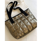 The FASHION GO Quilted Shoulder Tote Bag, available in assorted colors, features a metallic quilted design with black handles and rests on a white fabric surface—offering both style and functionality in a lightweight tote.