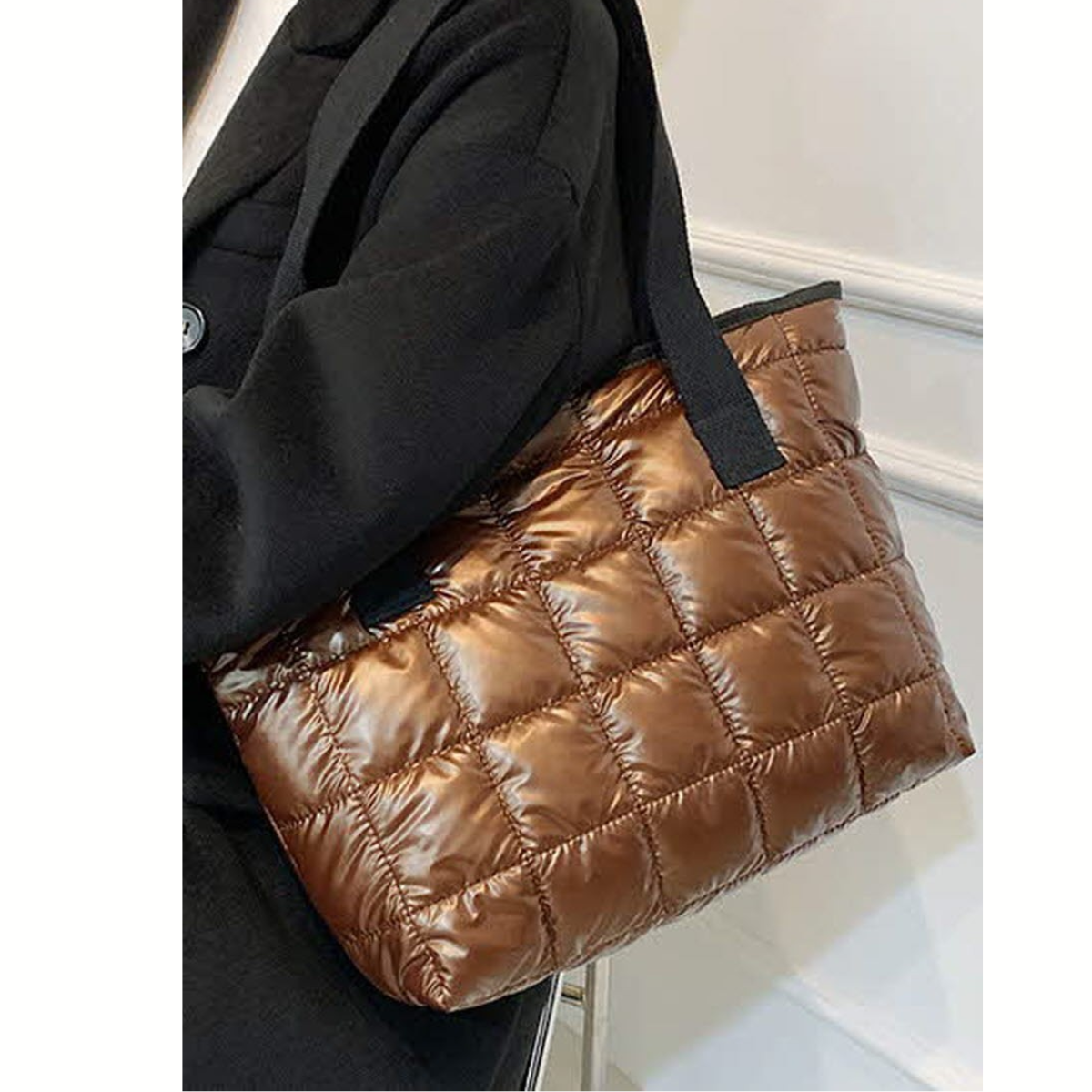 A person wearing a black coat carries the FASHION GO Quilted Shoulder Tote Bag – Assorted Colors with black straps over their shoulder.