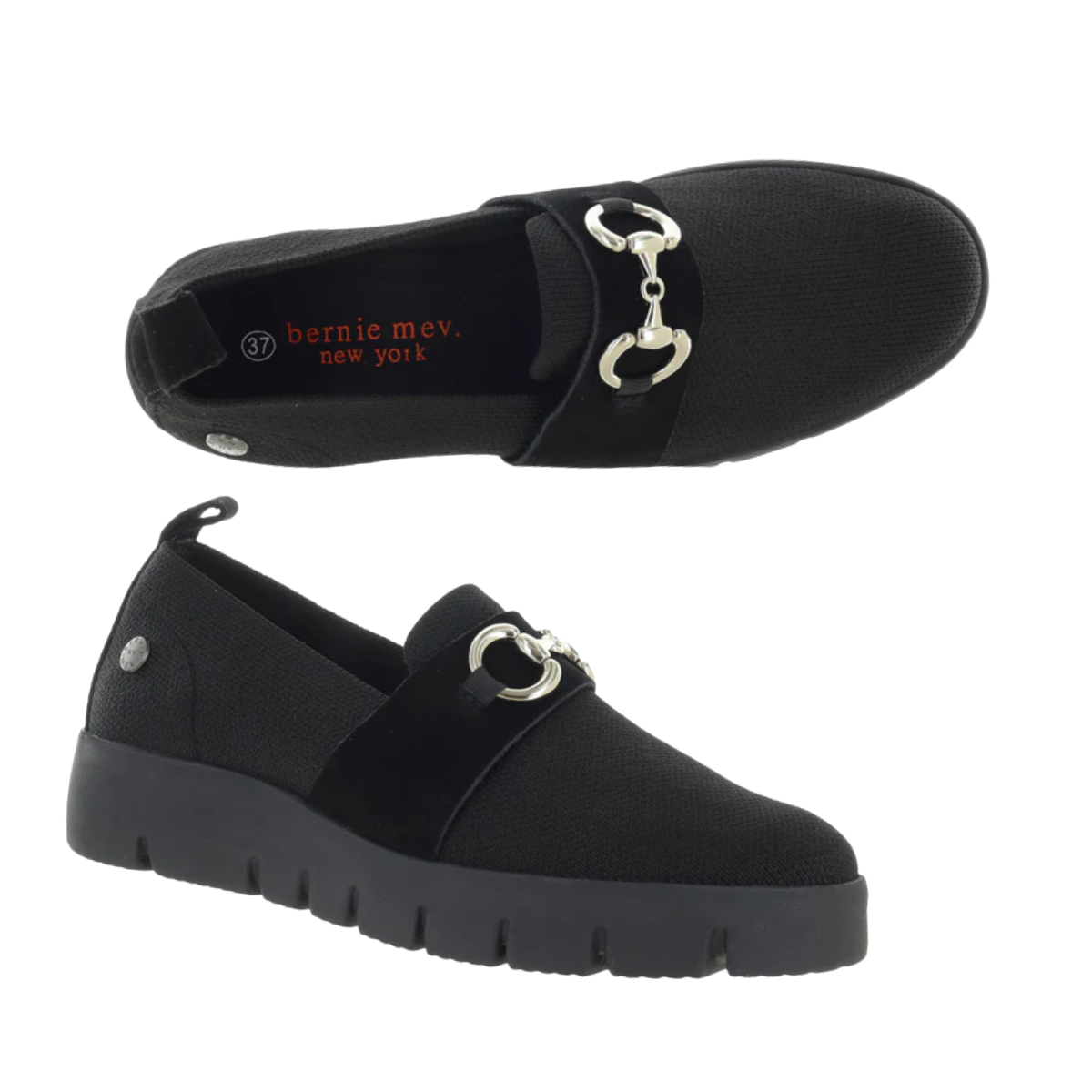 A pair of black Bernie Mex FX Monte slip-on shoes from BERNIE MEV, with lightweight woven uppers, thick soles, silver metal bit detail, memory foam footbed for comfort, shown in side and top views. Brand name visible inside.