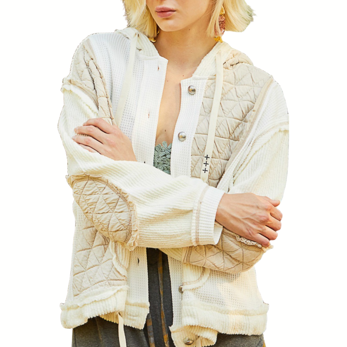 A woman with crossed arms wears the POL Quilted Jacket with Hoodie in cream and beige over a lace-trimmed top, standing against a white background—a perfect piece for fall layering.