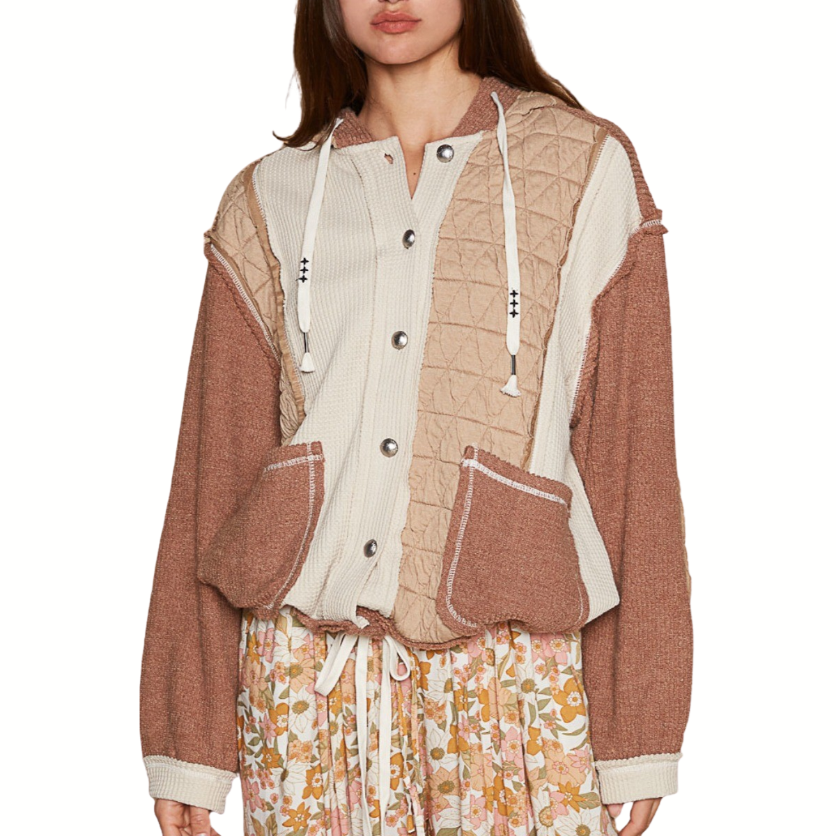 A woman wears the POL Quilted Jacket with Hoodie, featuring a patchwork design, button closure, drawstrings, and roomy pockets—ideal for fall layering—styled with a floral skirt.