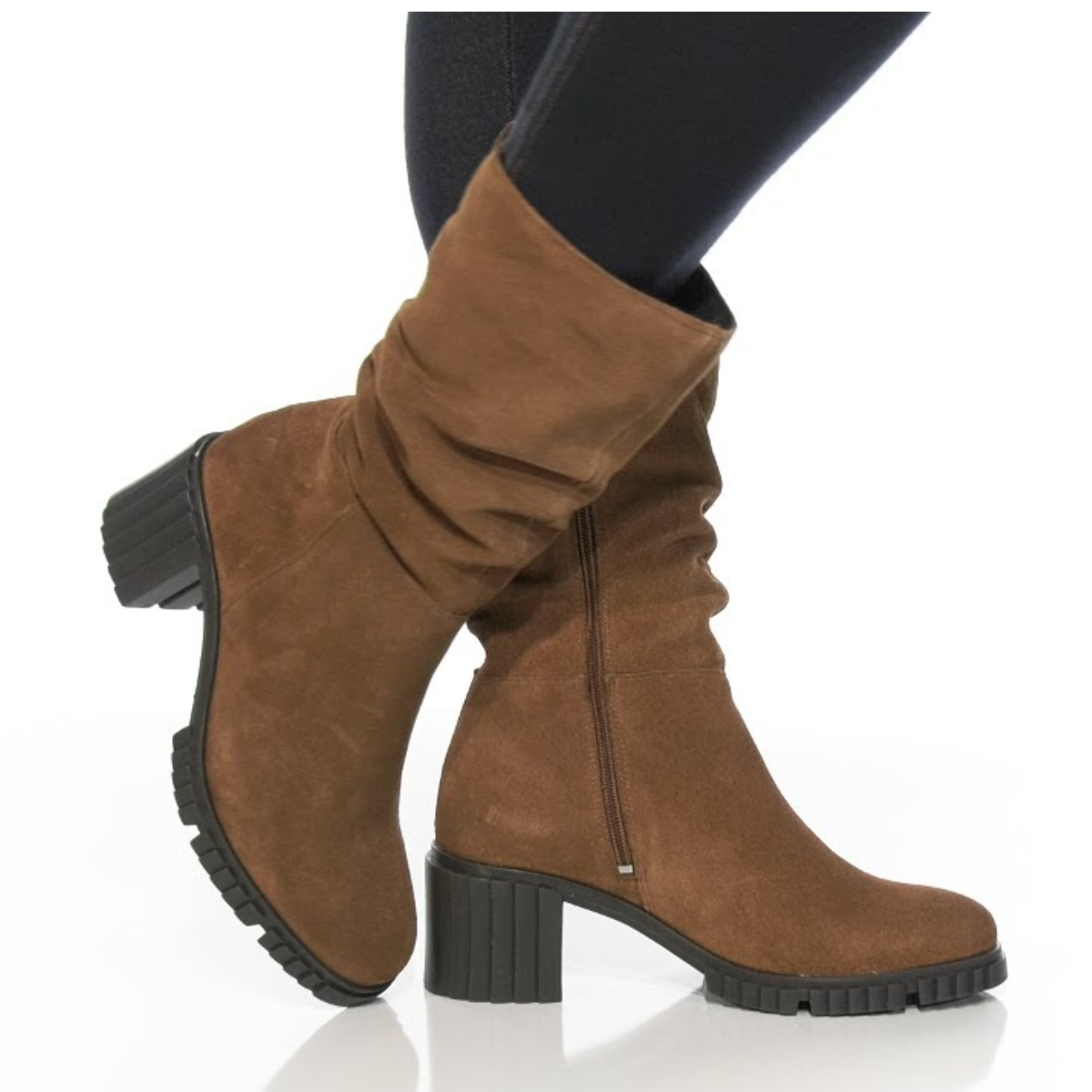 A person wearing black leggings and Eric Michael's Mercedes Suede Mid Shaft Boot, a brown women's stacked heel boot with side zippers, stands on a white background.