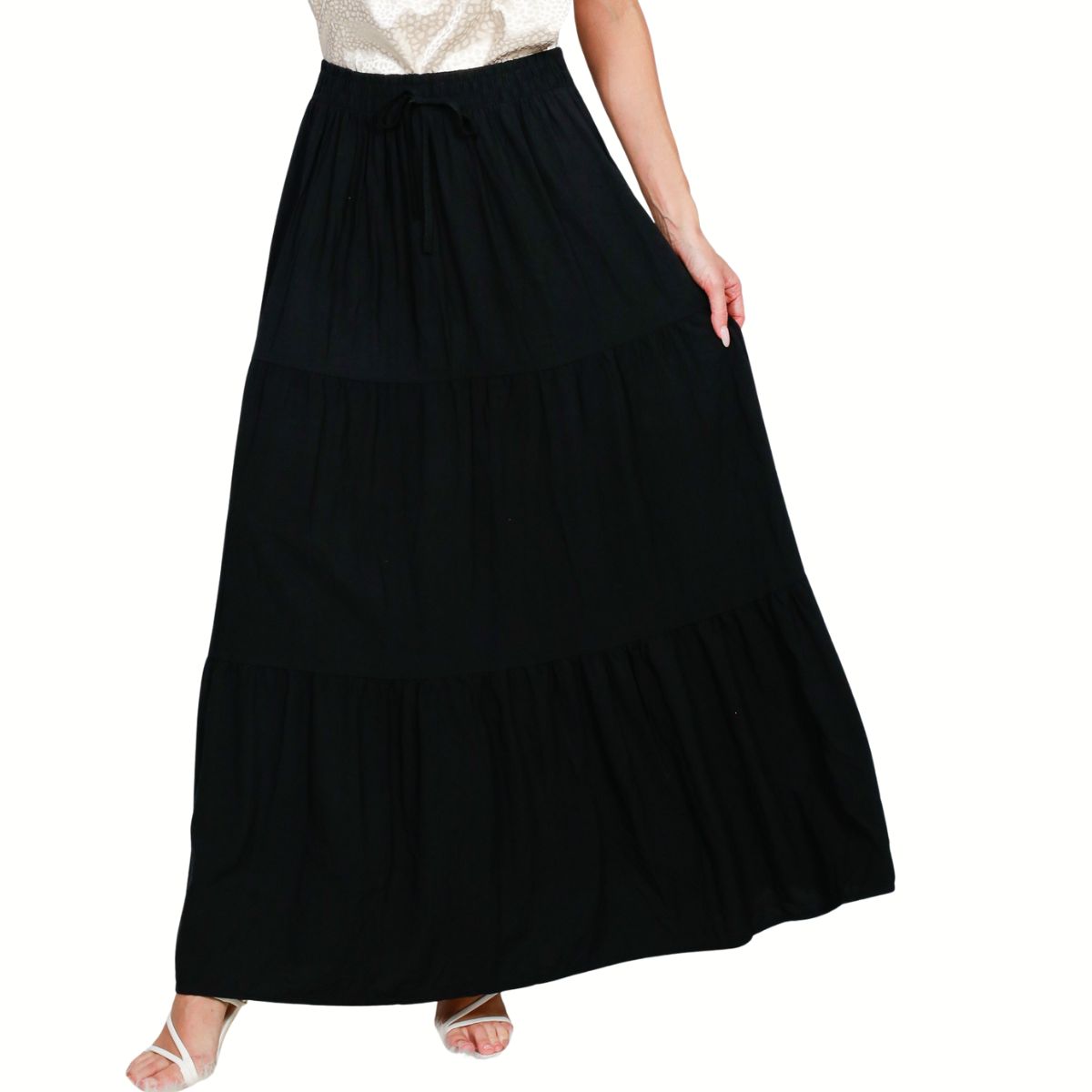 A person is seen from the shoulders down wearing a white top paired with the Fashiongo Tiered Maxi Skirt Black, featuring a long, tiered design and drawstring waist.