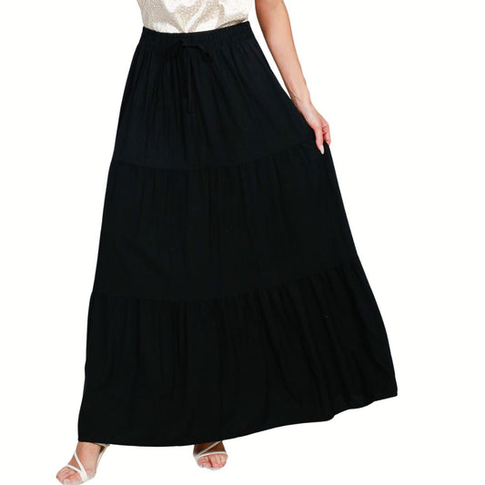 A person is seen from the shoulders down wearing a white top paired with the Fashiongo Tiered Maxi Skirt Black, featuring a long, tiered design and drawstring waist.