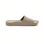 The Archies Slide Sandal in Taupe by ARCHIES FOOTWEAR LLC features a wide strap and contoured footbed. Displayed from the side on a white background, these beige slip-on slides offer excellent support.