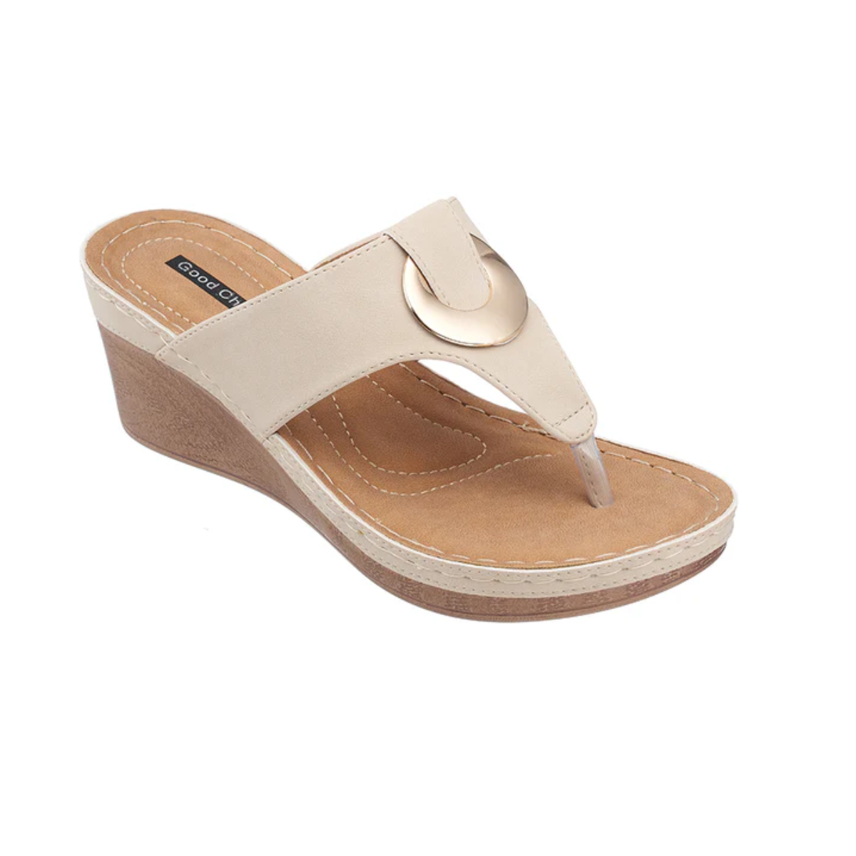 The Genelle Comfort Wedge Sandal by Good Choice features a beige leather top, open toe, wide strap with metallic circular accent, cushioned memory foam footbed, and a brown stitched sole.