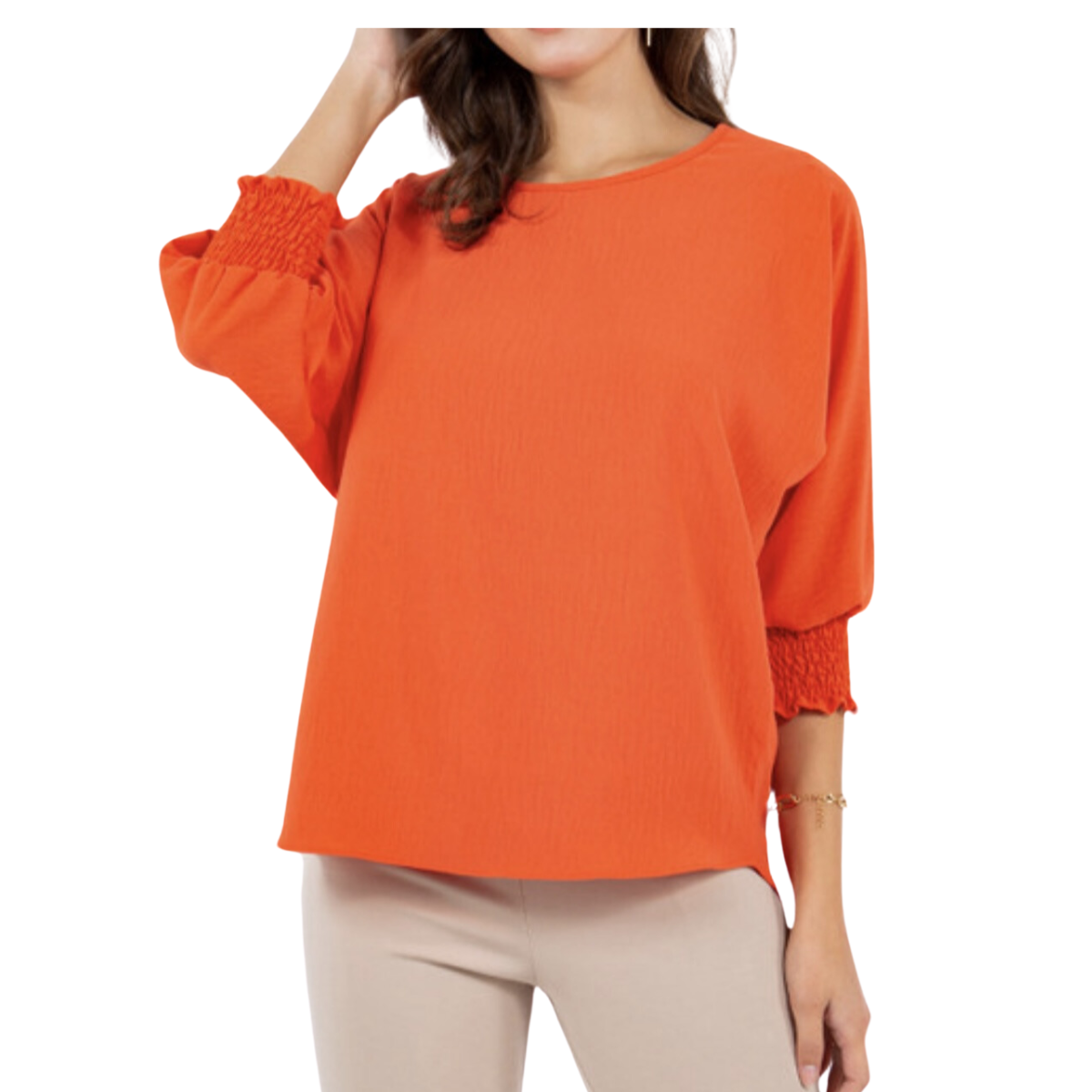 A person wearing a loose-fitting orange Smocked Sleeve Air Flow Top from Flipflops & Whatnots with 3/4 smocked sleeves that have gathered cuffs and light-colored pants. The boxy fit of the top adds to the casual elegance. The person's face is not visible.