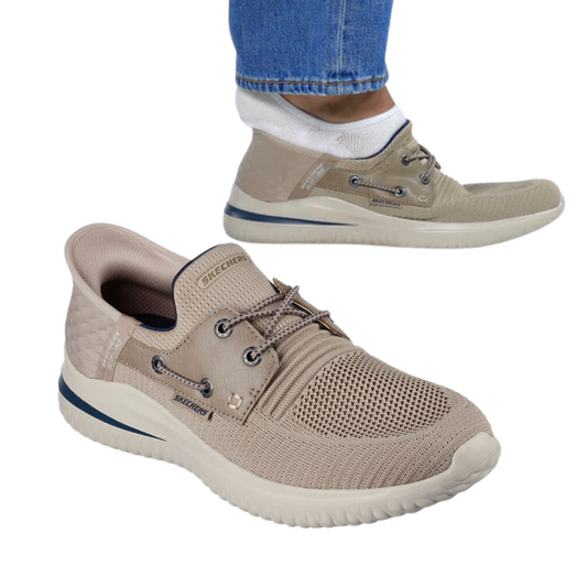 A pair of taupe Delson Men's Slip-ins by SKECHERS USA INC. One shoe is on the ground and the other is worn by a person in blue jeans. The shoes have white soles, mesh fabric uppers, and feature Air-Cooled Memory Foam for enhanced comfort.